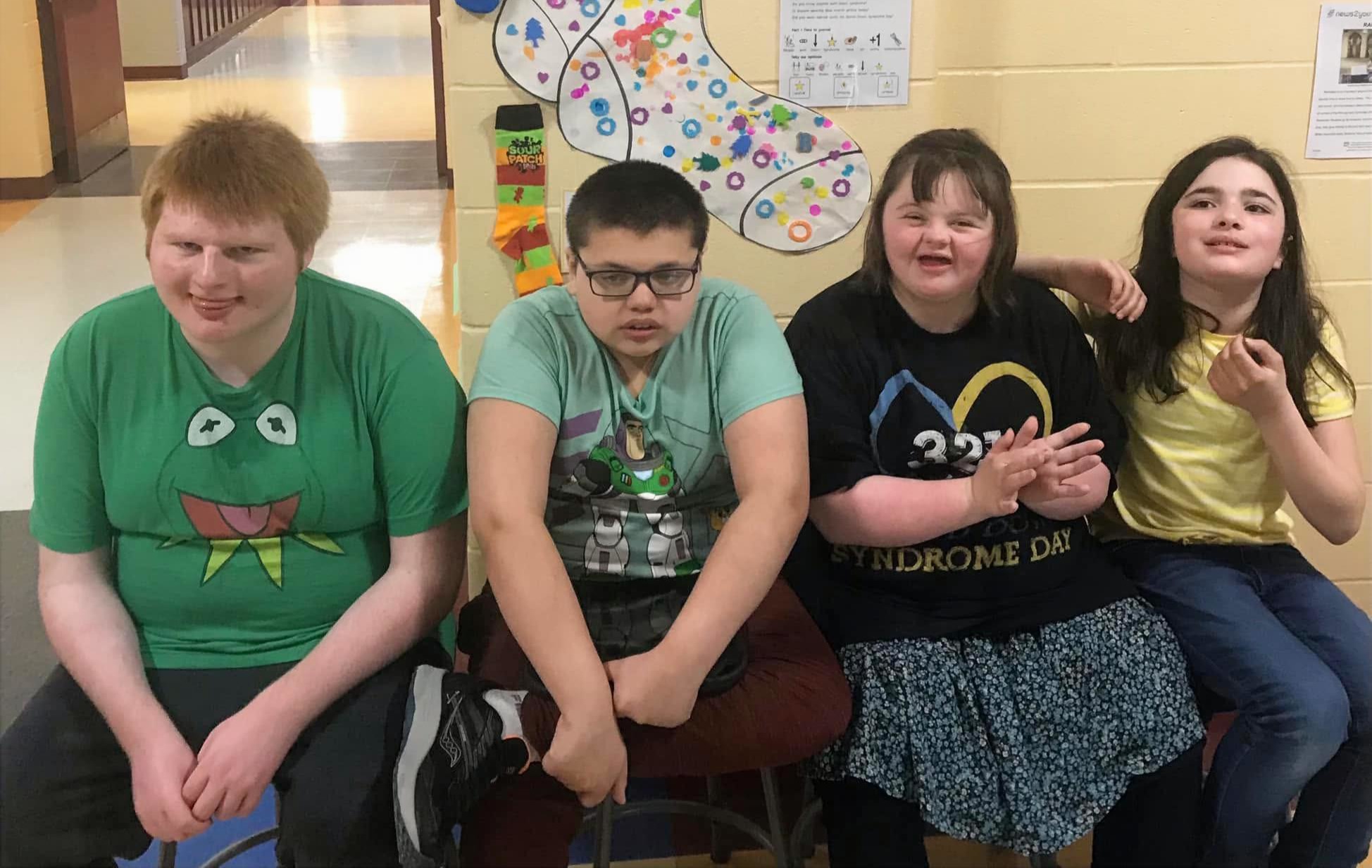 four kids sitting and smiling